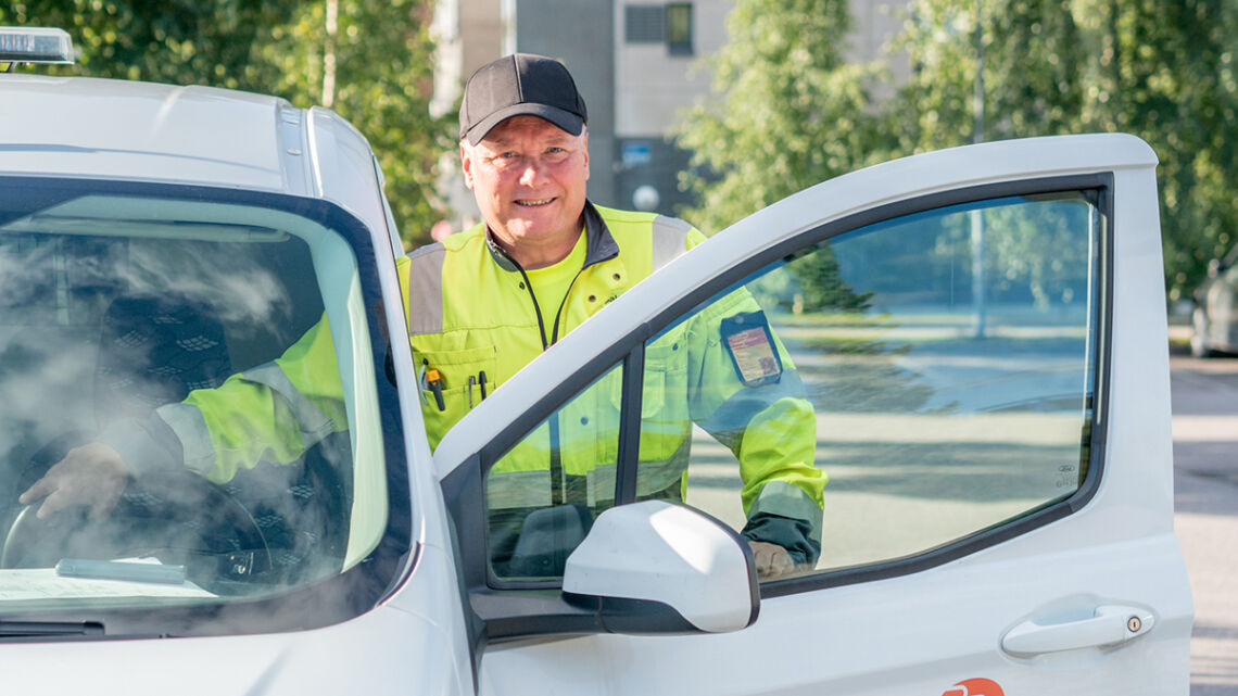 Palveluohjaaja Ari Murto kuvassa työautoon astumassa, auton ovi on auki ja taustalla näkyy vehreät koivut.